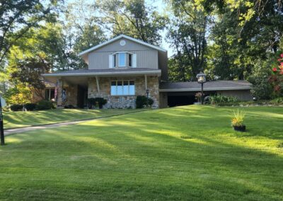 home with stonework and trees surrounding it